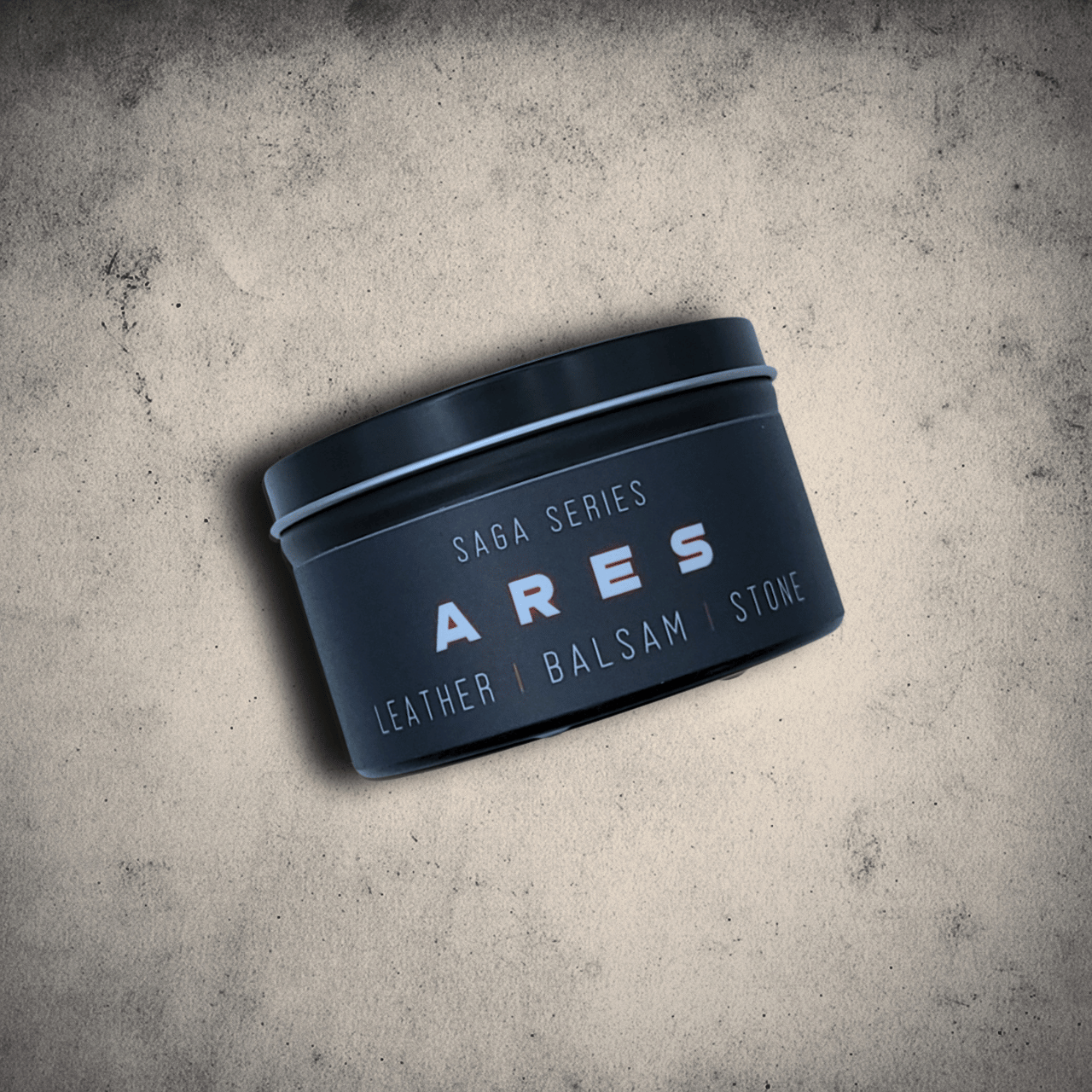 Emberlight Archives Ares candle in an 8oz black tin with black label against a gray stone background, Leather and Balsam scent.